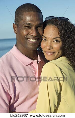 Stock Photo - Portrait of couple hugging on beach. Fotosearch
