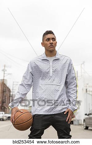 Picture - Portrait of curious Mixed Race man holding basketball. Fotosearch