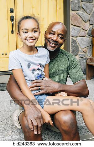 Stock Image - Portrait of girl sitting in lap of father. Fotosearch