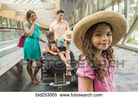 Stock Photography - Portrait of girl waiting in airport with family. Fotosearch