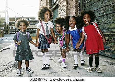 Stock Photograph - Portrait of girls laughing on sidewalk. Fotosearch