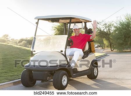 Stock Photography - Portrait of Hispanic golfer waving in golf cart. Fotosearch
