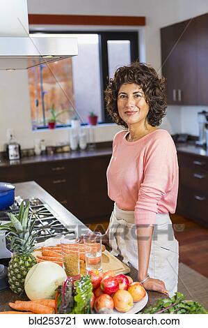 Stock Image - portrait of Hispanic woman in domestic kitchen. Fotosearch