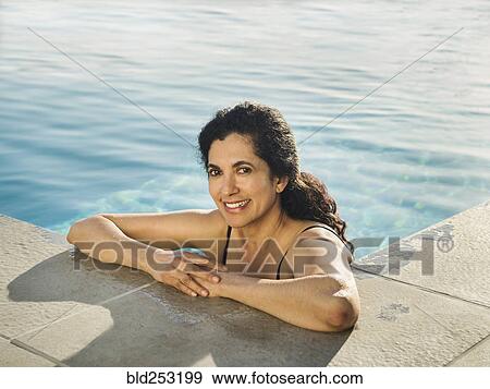 Stock Photo - Portrait of Hispanic woman relaxing in swimming pool. Fotosearch
