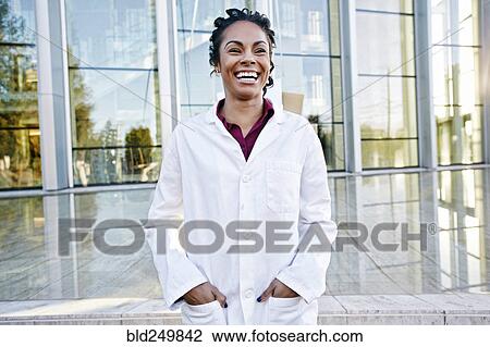 Stock Image - Portrait of laughing Mixed Race doctor outdoors at hospital. Fotosearch