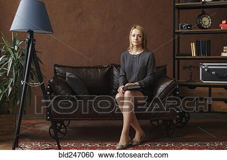 Stock Image - Portrait of Middle Eastern woman sitting on sofa. Fotosearch