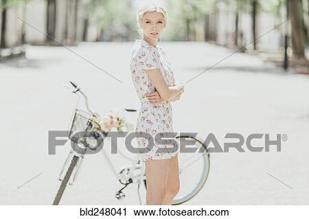 Stock Image - Portrait of Middle Eastern woman standing near bicycle. Fotosearch