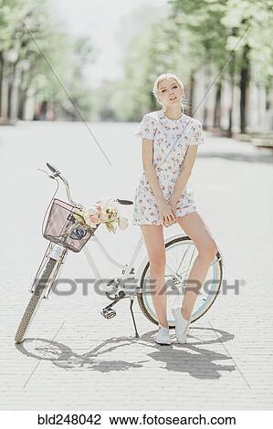 Stock Image - Portrait of Middle Eastern woman leaning on bicycle. Fotosearch