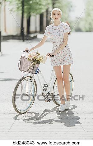 Stock Image - Portrait of Middle Eastern woman standing near bicycle. Fotosearch