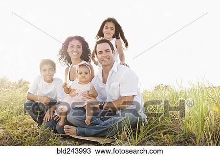 Stock Image - Portrait of Mixed Race family sitting in grass. Fotosearch