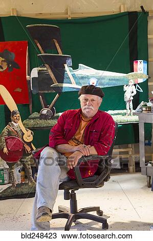 Stock Image - Portrait of older Caucasian man sitting in workshop. Fotosearch