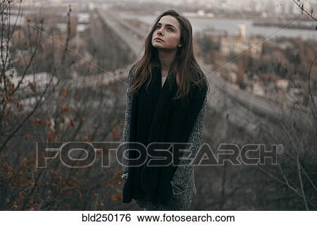 Stock Photograph - Portrait of pensive Caucasian woman standing on hill near freeway. Fotosearch