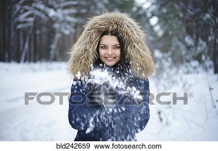 Stock Photo - Portrait of playful Caucasian woman throwing snow. Fotosearch