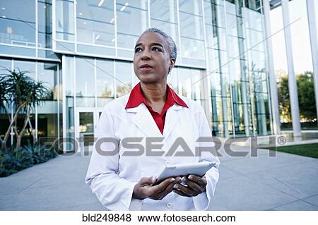 Stock Photo - Portrait of serious African American doctor holding digital tablet outdoors. Fotosearch