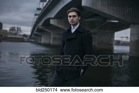 Picture - Portrait of serious Caucasian man standing under bridge. Fotosearch