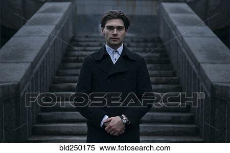 Portrait of serious Caucasian man standing near staircase View Large Photo Image Stock Photography - Portrait of serious Caucasian man standing near staircase. Fotosearch