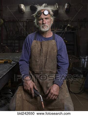 Portrait of serious Caucasian blacksmith in workshop holding torch View Large Photo Image Stock Image - Portrait of serious Caucasian blacksmith in workshop holding torch. Fotosearch