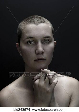 Picture - Portrait of serious Caucasian woman with shaved-head and hands clasped. Fotosearch