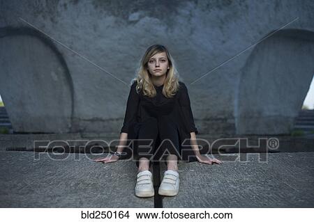 Portrait of serious Caucasian woman sitting on concrete View Large Photo Image Picture - Portrait of serious Caucasian woman sitting on concrete. Fotosearch