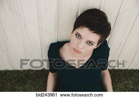 Stock Image - Portrait of serious Caucasian woman leaning on fence. Fotosearch