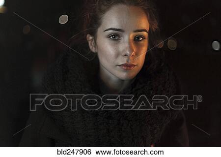 Stock Photograph - Portrait of serious Caucasian woman wearing scarf at night. Fotosearch
