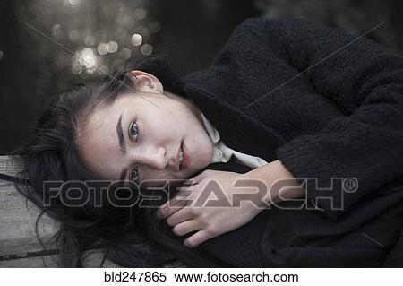 Stock Photography - Portrait of serious Caucasian woman laying on wood. Fotosearch