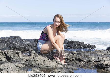 Portrait of serious Mixed Race woman sitting on rocks at beach View Large Photo Image Stock Photography - Portrait of serious Mixed Race woman sitting on rocks at beach. Fotosearch
