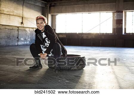 Portrait of smiling androgynous Asian woman sitting on wheel View Large Photo Image Stock Image - Portrait of smiling androgynous Asian woman sitting on wheel. Fotosearch