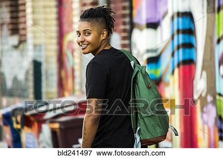 Stock Photo - Portrait of smiling androgynous Mixed Race woman near on graffiti wall. Fotosearch