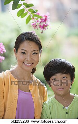 Portrait of smiling Asian mother and son near flowers View Large Photo Image Stock Photograph - Portrait of smiling Asian mother and son near flowers. Fotosearch