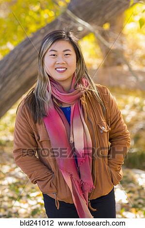 Stock Image - Portrait of smiling Asian woman in autumn. Fotosearch