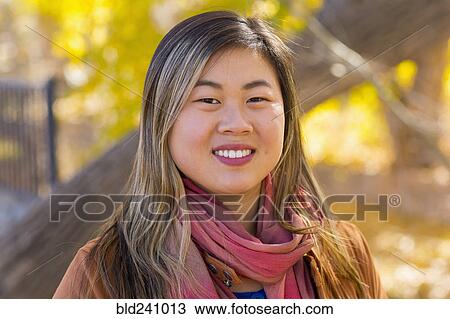 Stock Image - Portrait of smiling Asian woman in autumn. Fotosearch