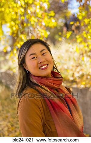Stock Image - Portrait of smiling Asian woman in autumn. Fotosearch