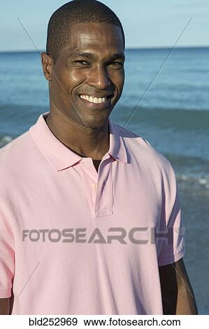 Stock Photo - Portrait of smiling Black man on beach. Fotosearch