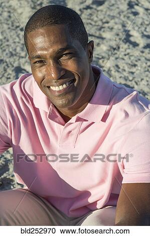 Portrait of smiling Black man sitting on beach View Large Photo Image Stock Image - Portrait of smiling Black man sitting on beach. Fotosearch