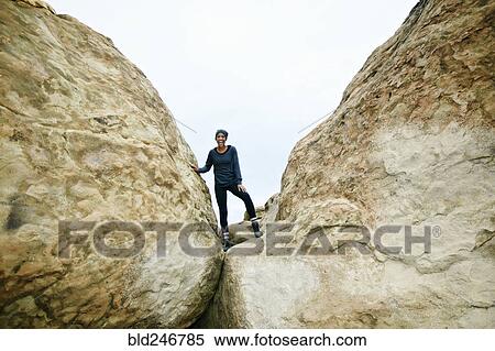 Stock Photography - Portrait of smiling Black woman posing on rock formation. Fotosearch