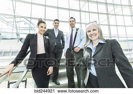 Stock Image - Portrait of smiling business people standing on staircase. Fotosearch