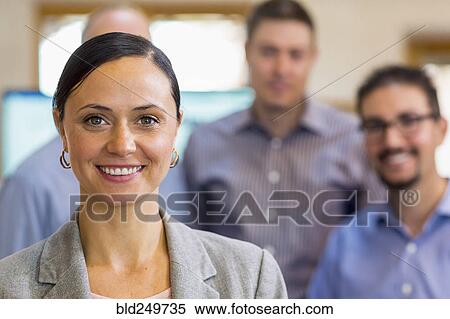 Stock Photography - Portrait of smiling businesswoman and team. Fotosearch