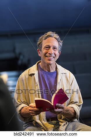Portrait of smiling Caucasian actor holding script in theater View Large Photo Image Stock Image - Portrait of smiling Caucasian actor holding script in theater. Fotosearch