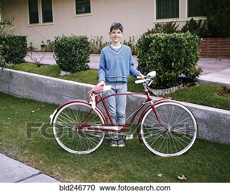 Stock Image - Portrait of smiling Caucasian boy posing with bicycle. Fotosearch