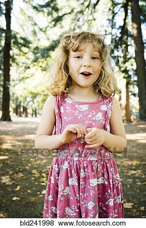 Stock Photo - Portrait of smiling Caucasian girl near trees. Fotosearch