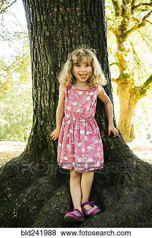 Portrait of smiling Caucasian girl leaning on tree View Large Photo Image Stock Photo - Portrait of smiling Caucasian girl leaning on tree. Fotosearch