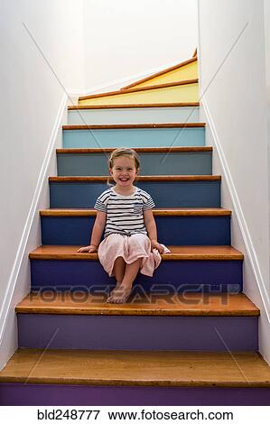 Portrait of smiling Caucasian girl sitting on multicolor staircase View Large Photo Image Stock Photo - Portrait of smiling Caucasian girl sitting on multicolor staircase. Fotosearch