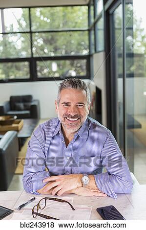 Portrait of smiling Caucasian man sitting at table View Large Photo Image Stock Photo - Portrait of smiling Caucasian man sitting at table. Fotosearch