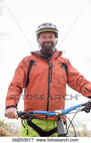 Portrait of smiling Caucasian man splattered in mud holding bicycle View Large Photo Image Stock Photo - Portrait of smiling Caucasian man splattered in mud holding bicycle. Fotosearch