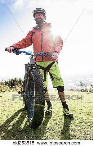 Stock Photography - Portrait of smiling Caucasian man splattered in mud holding bicycle. Fotosearch