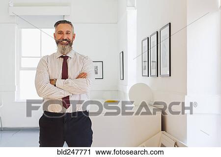 Stock Image - Portrait of smiling Caucasian businessman with arms crossed. Fotosearch