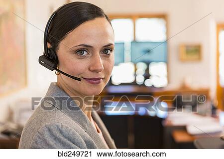 Stock Image - Portrait of smiling Caucasian businesswoman wearing headset. Fotosearch
