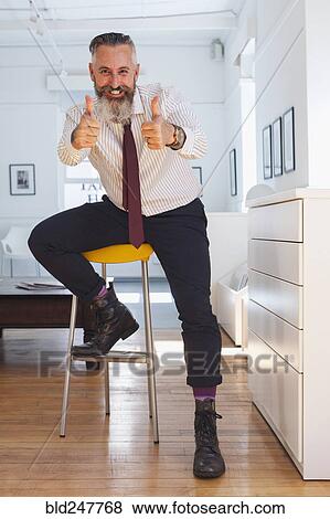 Stock Photo - Portrait of smiling Caucasian businessman gesturing thumbs up. Fotosearch