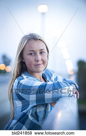 Stock Photo - Portrait of smiling Caucasian teenage girl leaning on railing. Fotosearch